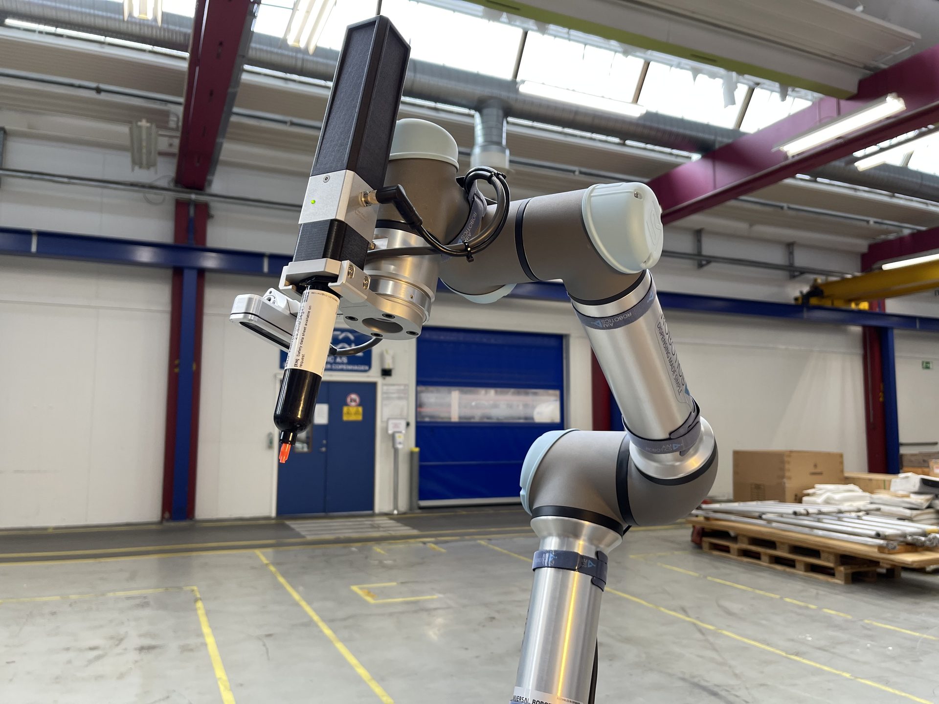 AimRobotics dispenser mounted on a Universal Robots cobot in an industrial facility